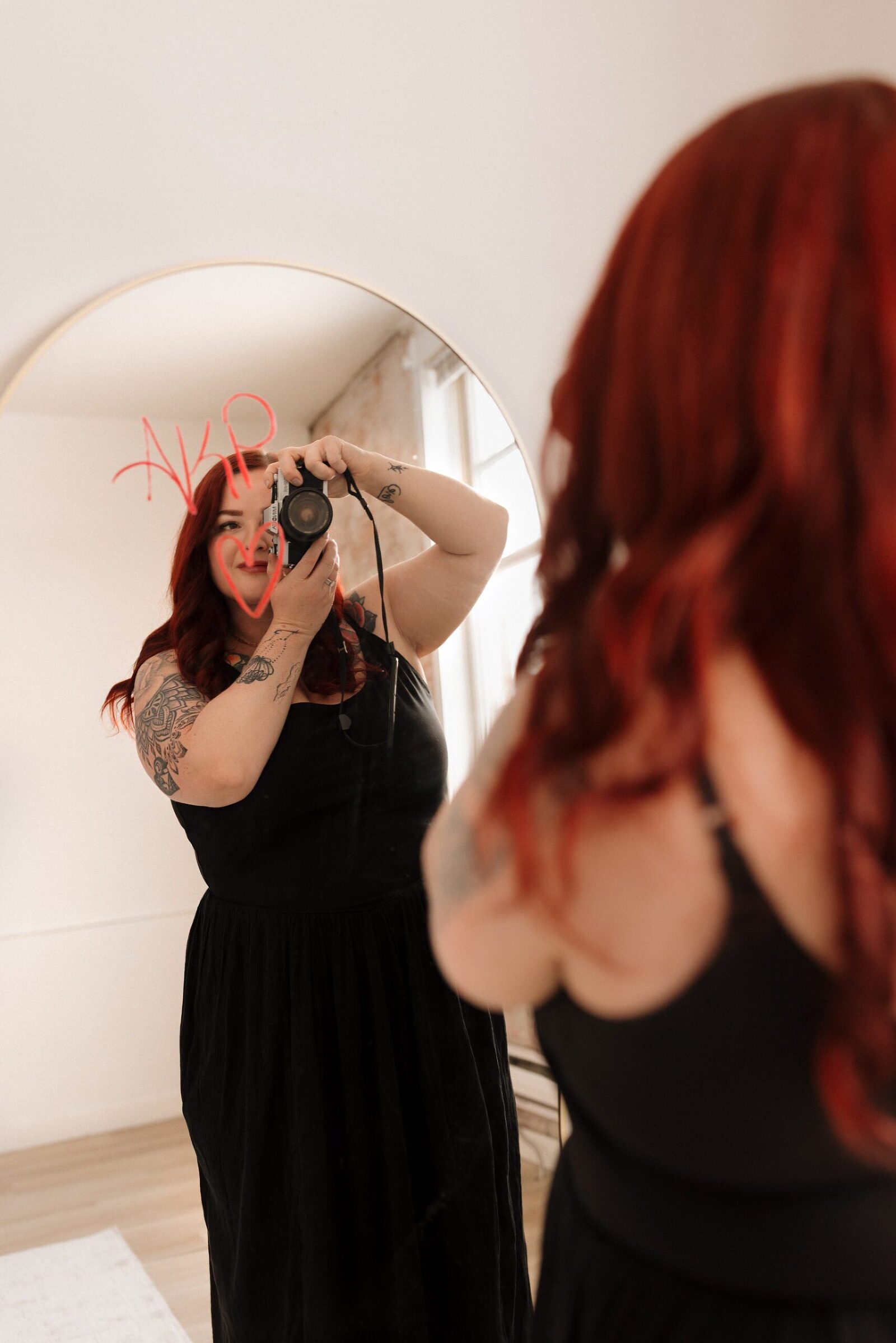Woman holding camera with reflection in mirror